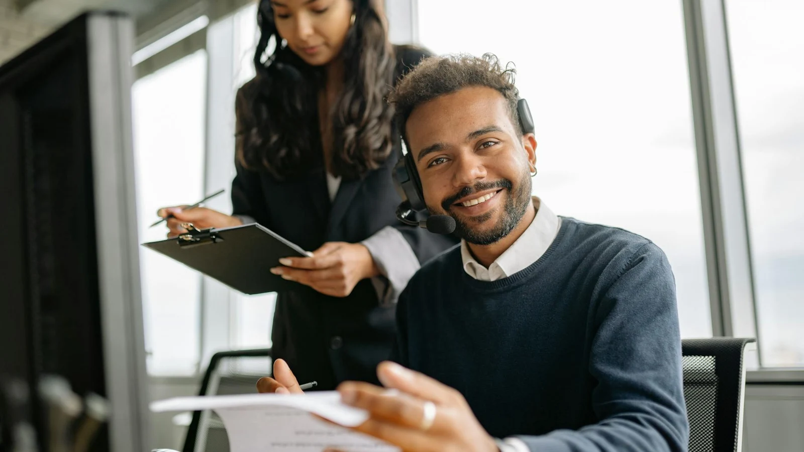 Welcoming customer service professional at a clean modern desk ready to assist with headset nearby